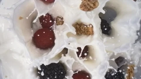 Granola with raspberry and blackberry falling into milk in slow motion Stock Footage 344848250