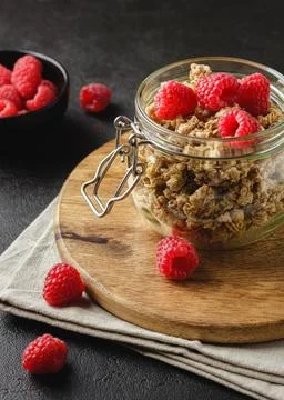 Granola with raspberry in jar on dark background. Stock Photos