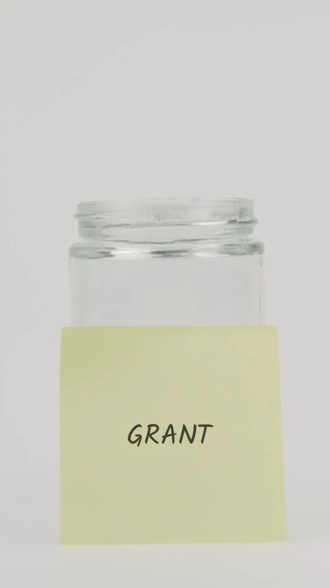 Grant text or word on yellow sticky note attached to glass jar with hand Stock Footage 311738933