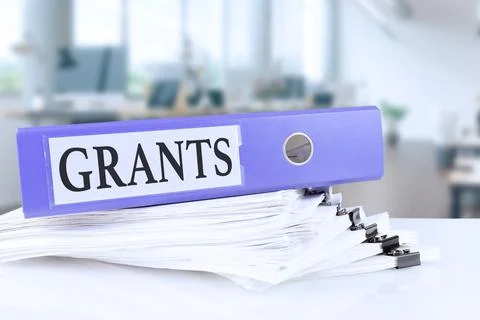 Grants, the term is written on a folder of documents in trendy purple, lying  Stock Photos