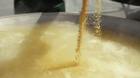 Granular ingredients poured into a steaming cooking pot Stock Footage 339285362