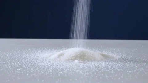 Granulated sugar streams down on a white table on a blue background Stock Footage 178442689