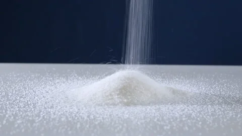 Granulated sugar streams down on a white table on a blue background Stock Footage 178445913