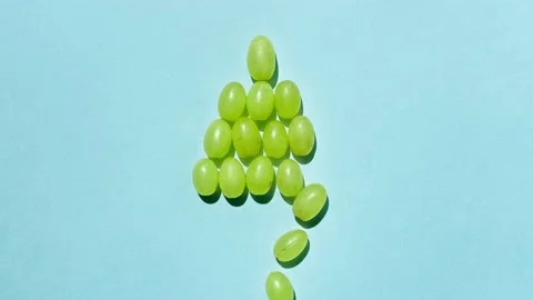 Grape berries shape a Christmas tree on a blue background. Stop motion Stockbeeldmateriaal 143492851
