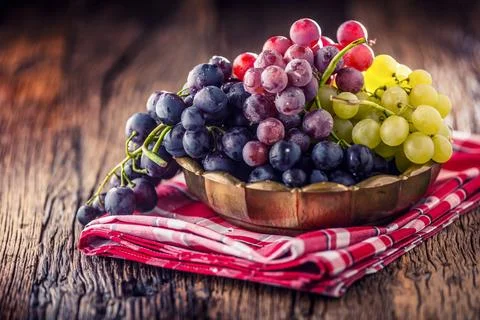 Grape. Bunch of multicolored grapes in retro bowl on old oak table 写真素材