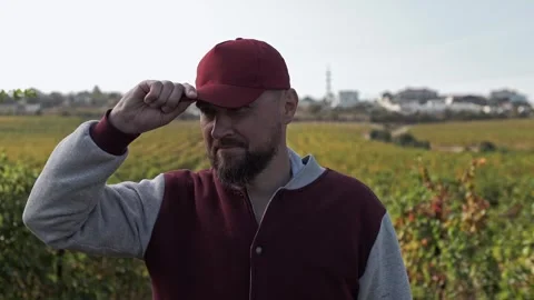 Grape picker smiles and adjusts his baseball cap in the grape terroir. Stock Footage 270065123