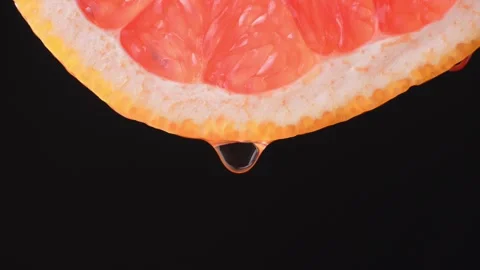 Grapefruit with dripping clear juice on black background 库存影片 248782429