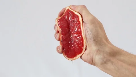 Grapefruit, hand squeezes out juice closeup Stock Footage 72239391