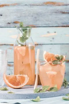 Grapefruit juice with mint in glasses on the table. Refreshing summer cocktai Stock Photos