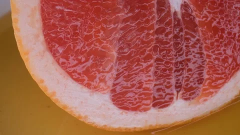 Grapefruit macro shooting,isolated half grapefruit on yellow background rotates Stock Footage 130996269