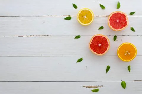 Grapefruit, orange and lemon half surrounded by mint leafs on a white rustic Stock Photos