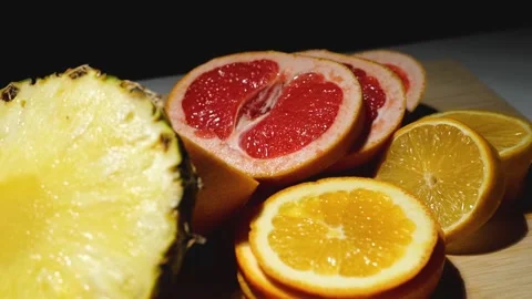 Grapefruit, oranges, lemon and pineapple sliced on a bamboo board Stock Footage 146146323