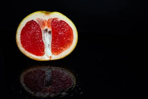 Grapefruit pulp with drops of moisture on a black mirror Stock Photos