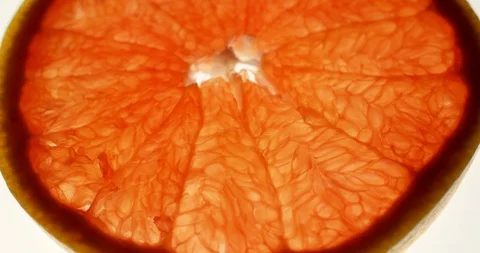 Grapefruit slice rotating on a bright white background. Close up view, shot on Stock Footage 107925932