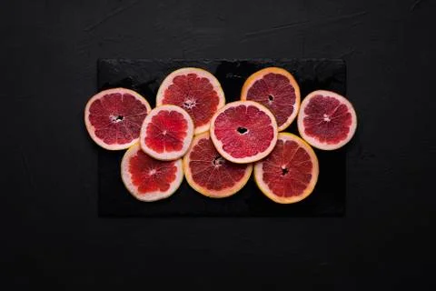 Grapefruit slices on a black table. Sliced fresh citrus fruit Stock Photos