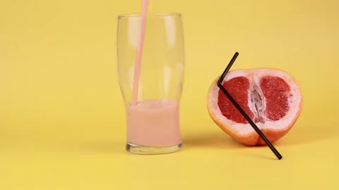 Grapefruit smoothie is poured into a glass beaker on a yellow background.  Stock Footage 152467344