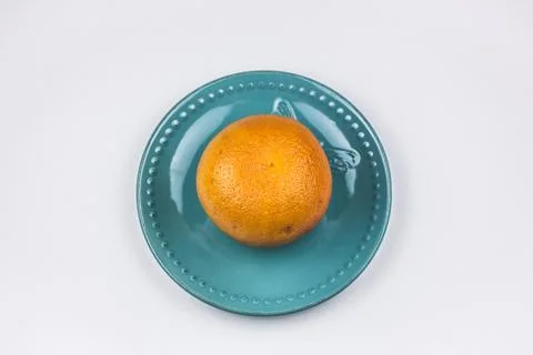 A grapefruit on a turquoise plate. Stock Photos