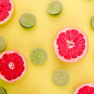 Grapefruits and limes split in half on yellow background Stock Photos