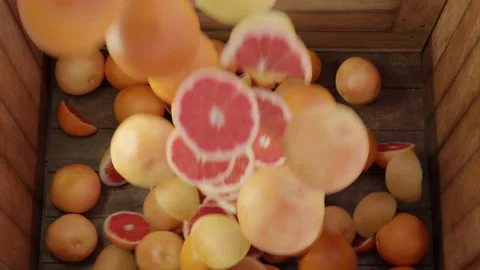 Grapefruits and oranges fall into a box. Fruit is poured into a box. loading of Vidéo 165239872