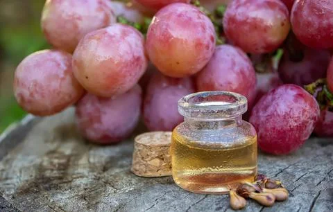 Grapes and a small jar of grape juice on a wooden surface Stock Photos