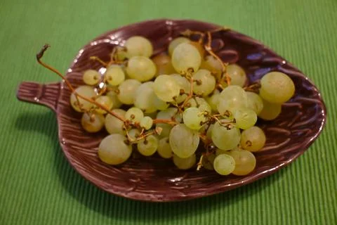 Grapes on a grape leaf-shaped ceramic plate Stock Photos