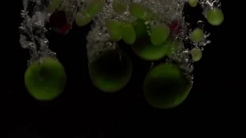 Grapes with lime will fall into the water in slow motion. on a black backgro Stock Footage 131036744