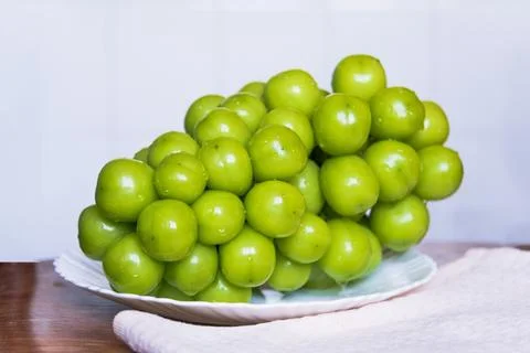 Grapes on a platter on a light background. Large seedless green grapes. Stock Photos