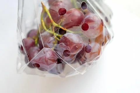 Grapes in transparent plastic packaging on a light background Stock Photos