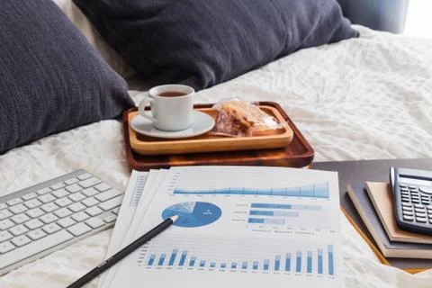 Graph analysis documents on bed with tea break. Stock Photos