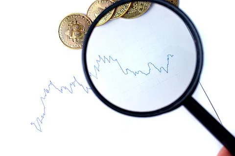 Graph of changes in exchange rates, magnifying glass and bitcoin coins on a w Stock Photos