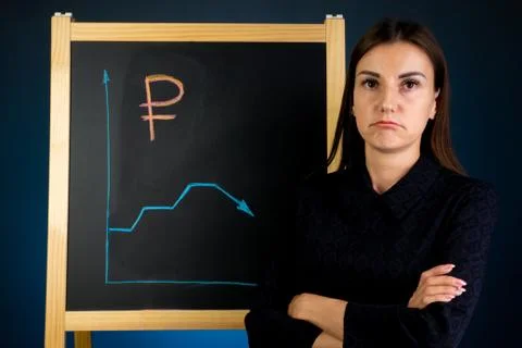The graph of the fall of the ruble is drawn on a black chalkboard, with a sad Stock Photos