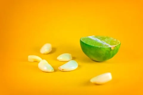 Graphic close up of a slice of lemon surrounded by garlic cloves over a backg Stock Photos