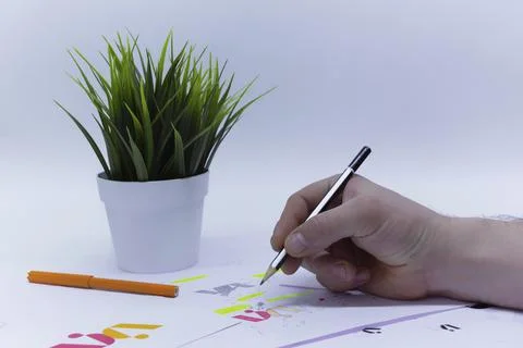 Graphic designer draws a logo in a creative studio on a light background with Stock Photos