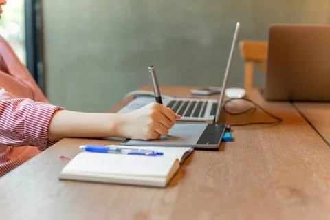 Graphic designer using digital tablet with laptop on the desk. Stock Photos