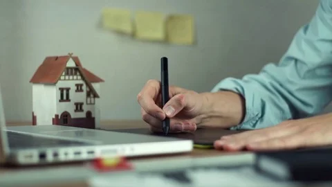Graphic designer using graphic tablet creating housing project on laptop Stock Footage 81880845