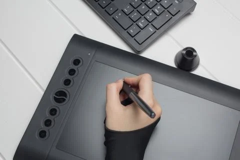 Graphic designer working on digital tablet. The hand draws on a graphics tabl Photos
