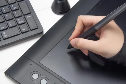 Graphic designer working on digital tablet. The hand draws on a graphics tabl Photos