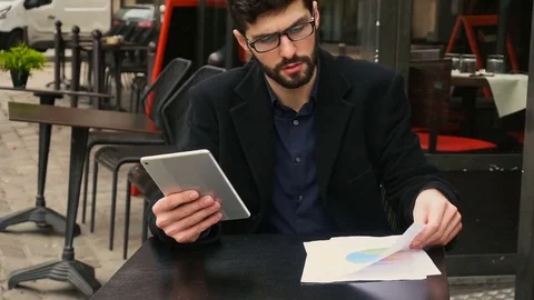 Graphic designer working with tablet and papers at cafe table in slow motion. Stock Footage 82718045