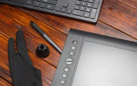 Graphic tablet, digital tablet and special pen, glove and keyboard on a woode 스톡 사진