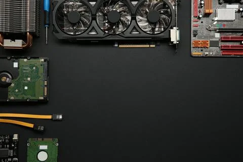 Graphics card and other computer hardware on black background, flat lay. Sp.. Stock Photos