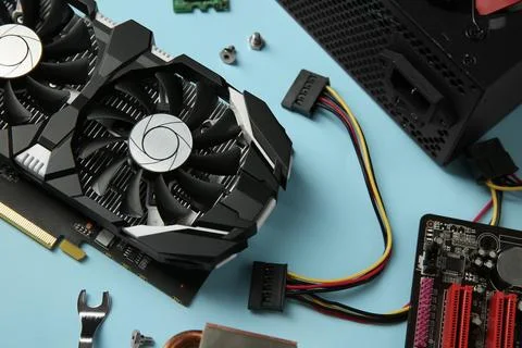 Graphics card and other computer hardware on light blue background, above vie Stock Photos