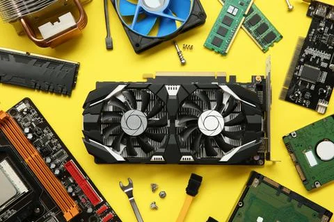 Graphics card and other computer hardware on yellow background, flat lay Stock Photos