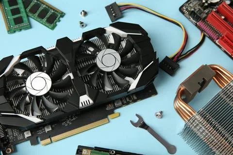 Graphics card and other computer hardware on light blue background, above vie Stock Photos