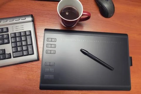 Graphics tablet with a pencil, part of the notebook and cup of coffee on a bl Foto stock