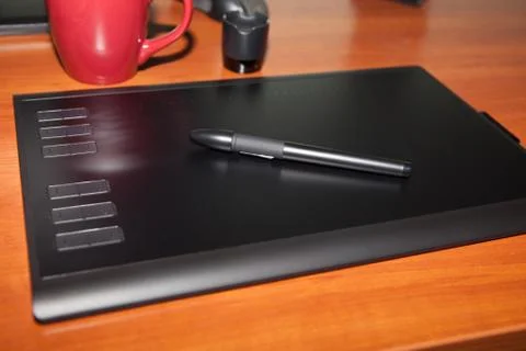 Graphics tablet with a pencil, part of the notebook and cup of coffee on a bl Stock Photos