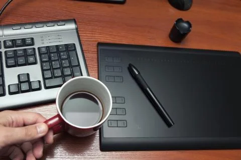 Graphics tablet with a pencil, part of the notebook and cup of coffee on a bl Stock Photos