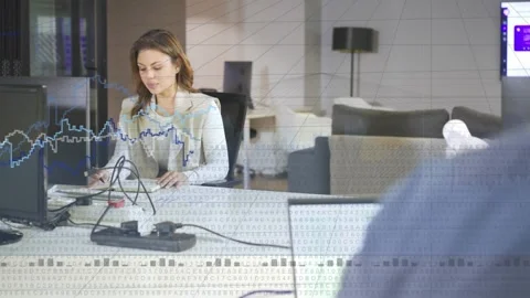 Graphs rising woman tracking analytics taking notes adjusting cables as coworker Video stock 334308421