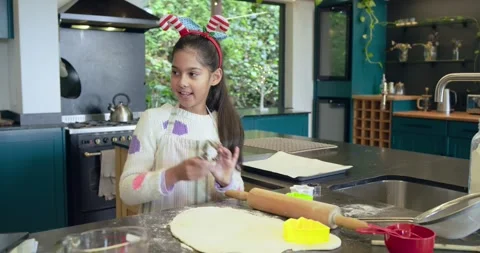 Grasping cookie cutter, Indian child pressing dough smoothing with pin in Stock Footage 340256897