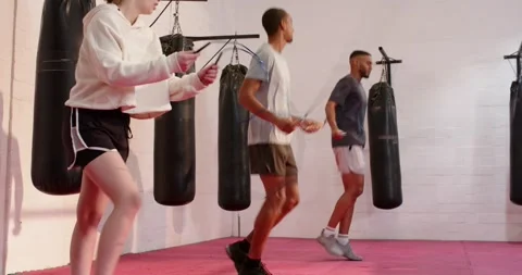Grasping jump ropes, training partners skipping on gym floor in front of Видео 343836985