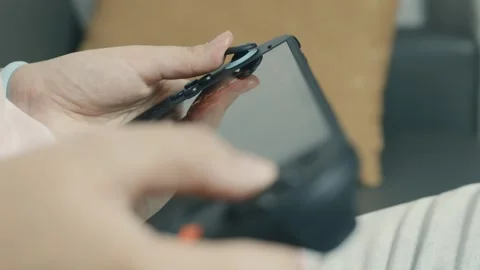 Grasping modern Nintendo Switch 2 gaming console with large screen, showcasing Stock Footage 312441559